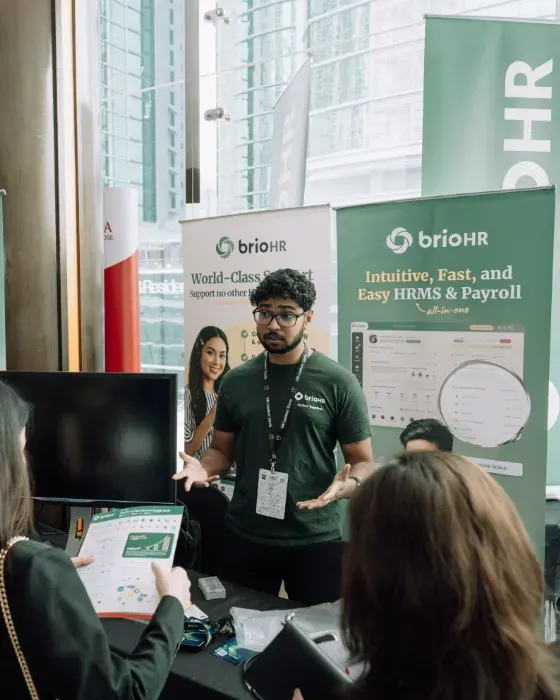 A brioHR team member talking with visitors at an HR event booth